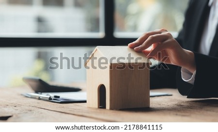 Real estate agents hold models of housing estates in projects to elaborate to clients, explaining and presenting information about homes and purchasing loans. Real estate trading concept.