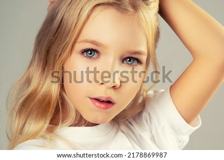Portrait of cute european little girl over pink background. Looking at camera. Child model in white T-shirt. Advertising childrens products