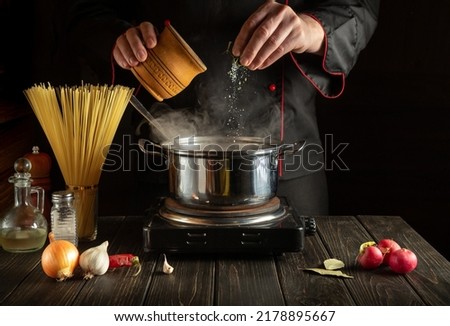 Experienced chef adds salt to Stock pot of boiling water. Cooking Italian spaghetti in the kitchen. 