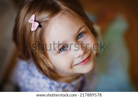 A little cute smiling girl looking upwards close up.