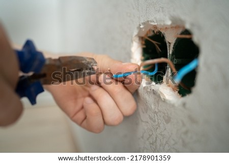 man works with electrical wires using tools, fixing socket at home, male household work with electricity, pliers and wire cutters in man's hands, electrician working with wire Royalty-Free Stock Photo #2178901359
