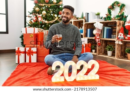 Young african american man smiling happy celebrating 2022 new year drinking champagne at home.