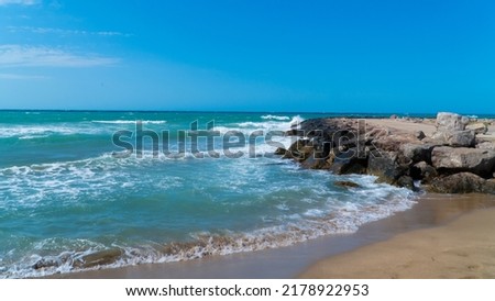 Waves hitting the shore. Wavy sea. Sand beach. Rough waves hitting the rocks.
