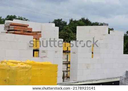 A house under construction, walls made of acc blocks, rough windows and door openings, reinforced brick lintels, a scaffolding, insulated foundation walls, solid concrete blocks and acc blocks Royalty-Free Stock Photo #2178923141