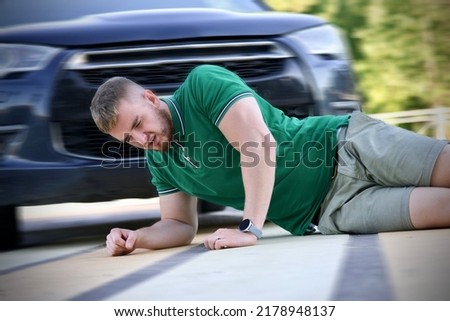 Young downed man at accident scene, crash on the road on crosswalk. Pedestrian guy hit by careless driver in a car on the road while crossing highway, person is lying on asphalt. Dangerous situation Royalty-Free Stock Photo #2178948137