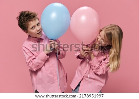 school-age children stand holding balloons in their hands and look out from behind them smiling. Horizontal photo on an empty pink background with space for inserting advertising text