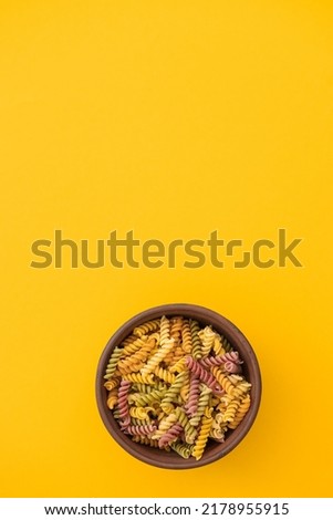 Beautiful Italian uncooked colored farfalle pasta close-up on yellow background. horizontal top view