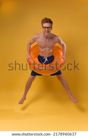 Full size photo of young man happy smile jump with swimming ring isolated over yellow color background