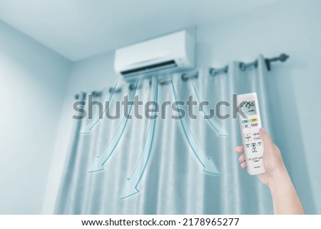 woman holding air conditioner remote control with air conditione