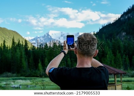 A man photographs mountains. A tourist photographs the landscapes of Altai. A tourist photographs the forest. A tourist photographs the sights of Altai. Altai Mountains.