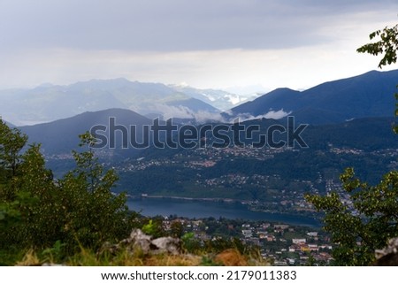 Scenic landscape with mountain panorama and Lake Lugano seen from local mountain San Salvatore at City of Lugano on a cloudy summer day. Photo taken July 4th, 2022, Lugano, Switzerland.
