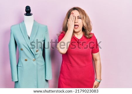 Middle age caucasian woman standing by manikin yawning tired covering half face, eye and mouth with hand. face hurts in pain. 