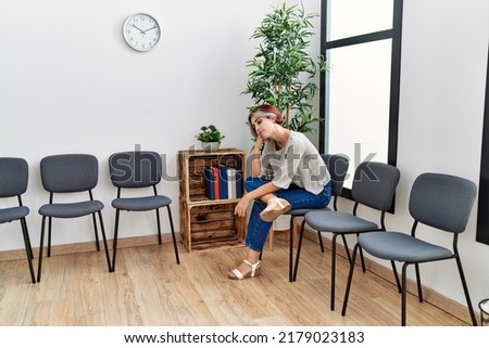 Young caucasian girl bored sitting on the chair at waiting room.