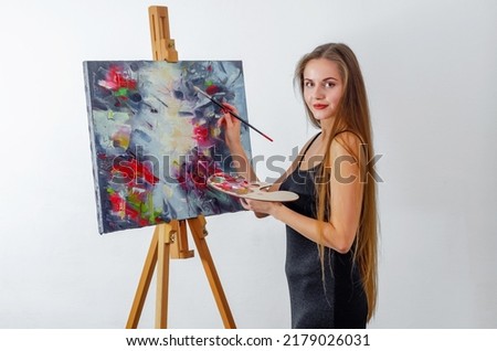 Woman artist paints picture on canvas on an easel
