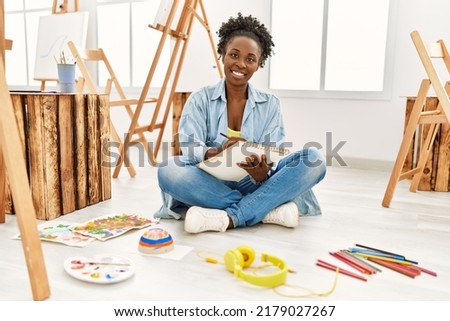 Young african american artist woman smiling happy drawing at art studio. Royalty-Free Stock Photo #2179027267