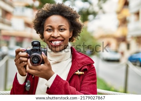 Young african american woman holding dslr camera at the city