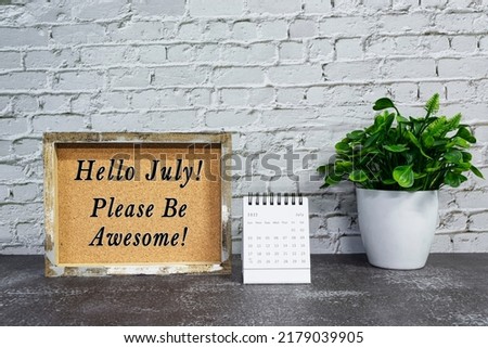 Motivational quote on wooden frame with July 2022 calendar - Hello july, please be awesome.