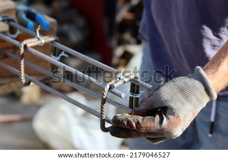 Hand holding reinforcement steel. Professional construction worker.  Close up photo of builder's hands in protective gloves.  Royalty-Free Stock Photo #2179046527