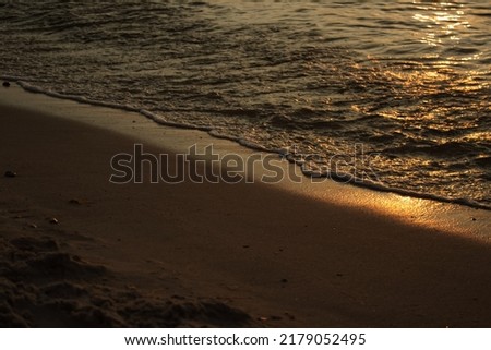 Sandy beach against the backdrop of sea waves at sunset