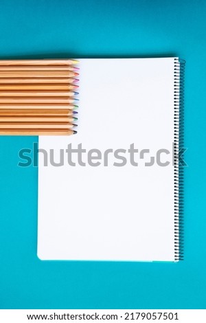 wooden colored pencils on blank page of a notebook