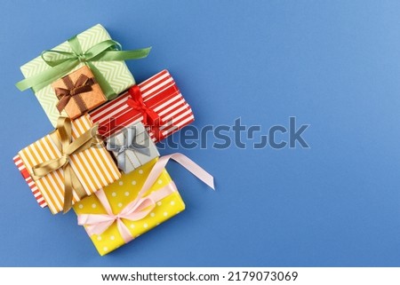 Presents in colorful wrapping paper with ribbon bows on blue isolated background. Flat lay. Festive gift concept. Top view.