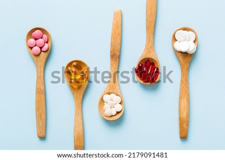 Vitamin capsules in a spoon on a colored background. Pills served as a healthy meal. Red soft gel vitamin supplement capsules on spoon. Royalty-Free Stock Photo #2179091481