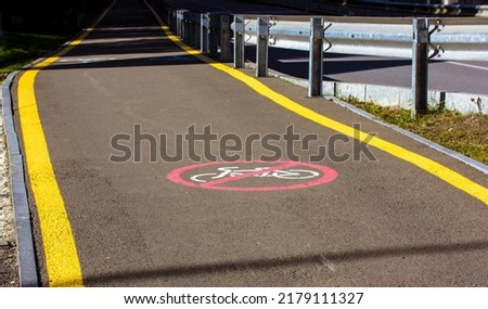 Trail for hikers with special yellow markings on the asphalt road going into a distance and a round red sign prohibiting cycling here. Infrastructure at the resort for safe travel. No bicycles concept