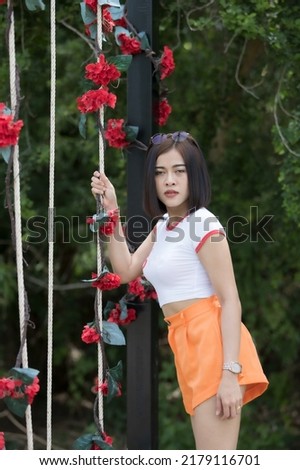A smart woman model short hair in white shirt and orange shorts, she acting for take a picture on swing is happy, take a photo on cafe and indoor ,outdoor studio