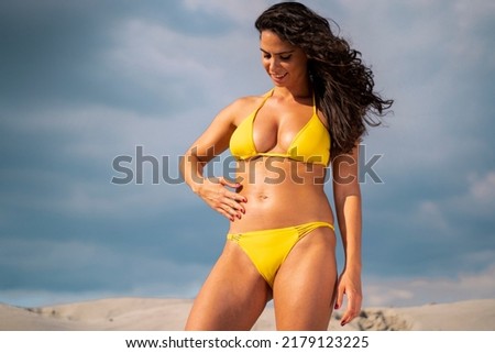 Beautiful young woman in yellow bikini applying sunscreen on her body