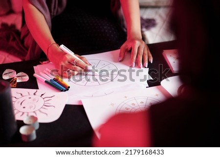 Closeup image of female astrologer drawing natal card for female client Royalty-Free Stock Photo #2179168433