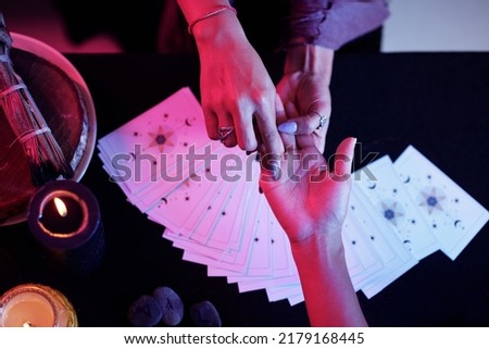 Fortune teller pointing at love line on palm of female client Royalty-Free Stock Photo #2179168445