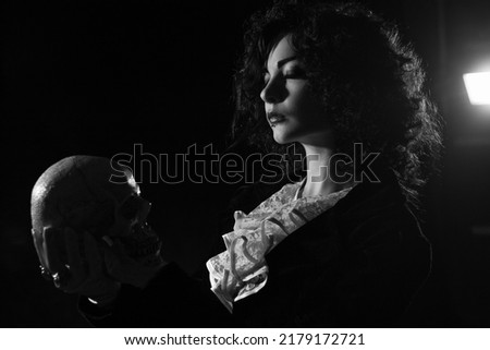 Pretty old fashioned girl posing with skull over dark background