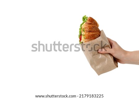 Croissant in a paper packaging bag mockup, take away food. Take away fresh french croissant with cheese and lettuce in paper bag. Copy space., place for text Royalty-Free Stock Photo #2179183225