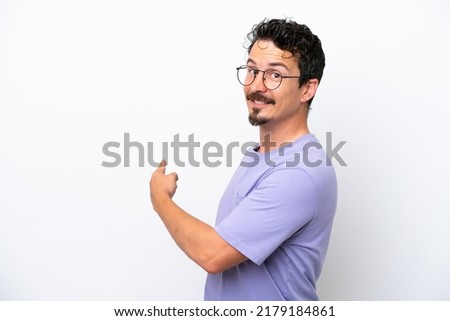 Young man with moustache isolated on white background pointing back Royalty-Free Stock Photo #2179184861