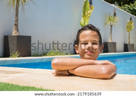 Happy young boy relaxing on the side of a swimming pool. Summer holidays concept.