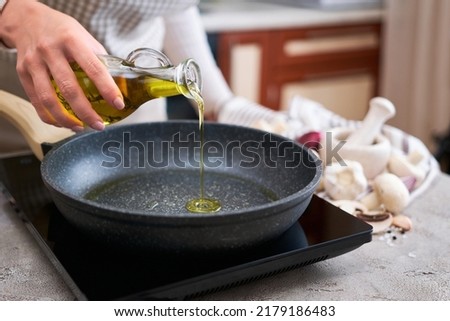 Woman pouring olive oil on frying pan at domestic kitchen Royalty-Free Stock Photo #2179186483