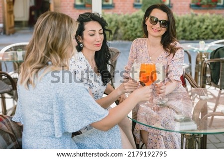 Happy beautiful women relaxing and drinking cocktails in cafe. Outdoors. Summer lifestyle.
