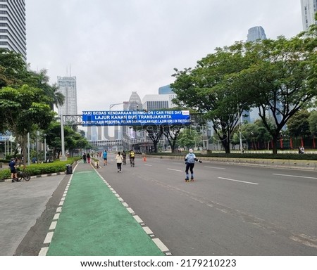 empty street on Sunday car free day, translate: car free day, right lane for transjakarta bus following by cyclist, runner and walker on left lane or sidewalk Royalty-Free Stock Photo #2179210223