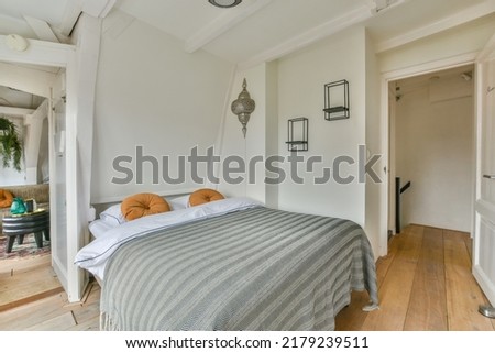 Comfortable bed and lamp placed in small narrow minimalist style bedroom with white walls and window in modern apartment Royalty-Free Stock Photo #2179239511