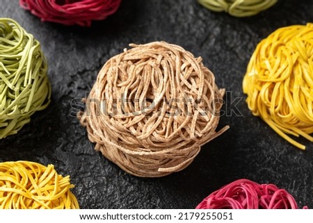 Dry whole wheat, beetroot, spinach and egg noodles on rustic dark background Royalty-Free Stock Photo #2179255051
