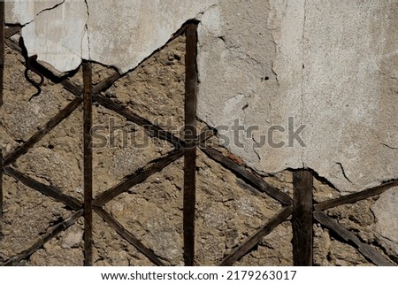 Tradirional timber framing with worn out cement rendering on old rustic wall, architecture detail