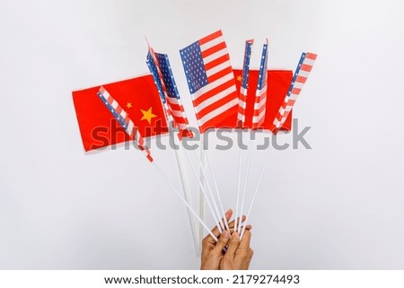 Closeup studio shot of small miniature fabric cloth paper pride Chinese nation people republic of China and USA United States of America country national flags with sticks placed on white background.