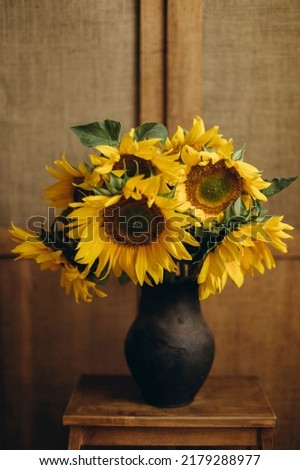 a bouquet of sunflowers in an old clay vase on the background of a wooden sideboard.