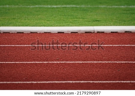 Running racetrack standard rubber surface with white lane outline. Sport and background photo. Selective focus.