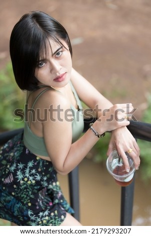 A woman model short hair in fashion suit take a photo on outdoor and studio and natural light, and she like a americano ice coffee