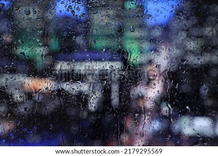 Raindrops on glass close-up. Natural pattern of raindrops isolated on the background of the night city.