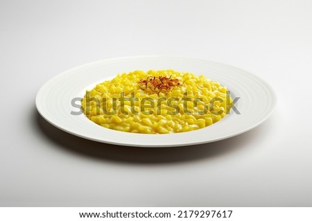 White flat plate with yellow risotto and saffron pistils isolated on white background Royalty-Free Stock Photo #2179297617
