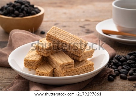 Wafer with coffee flavored cream in white plate with cup and coffee bean background Royalty-Free Stock Photo #2179297861