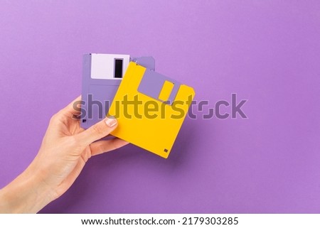 Hand holding floppy disk on color background, technology concept