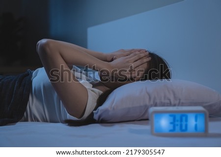 woman have insomnia on the bed selective focus on alarm clock at three in the morning. Royalty-Free Stock Photo #2179305547